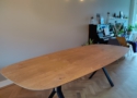 De rechthoekige eiken eettafel 280cm is 3cm dik gelaagd en is gemaakt van massief gestabiliseerd eikenhout met afgeronde hoeken en een spreidpoot met eiken inleg